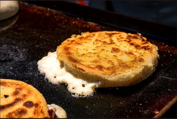 Arepa dorada en la plancha con queso derretido